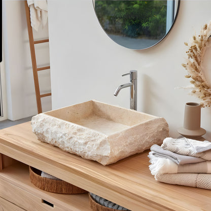 Light yellow travertine wash basin with raw rough edge texture above counter stone sink wabi-sabi bathroom decor