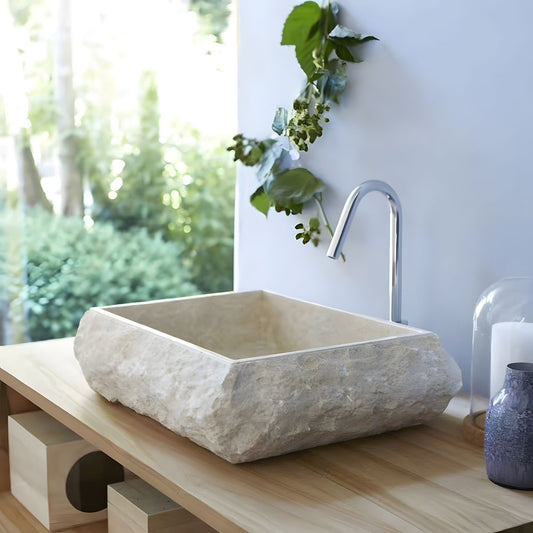Rough chiseled beige travertine vessel sink rectangular natural stone basin 45° shot on wooden bathroom vanity